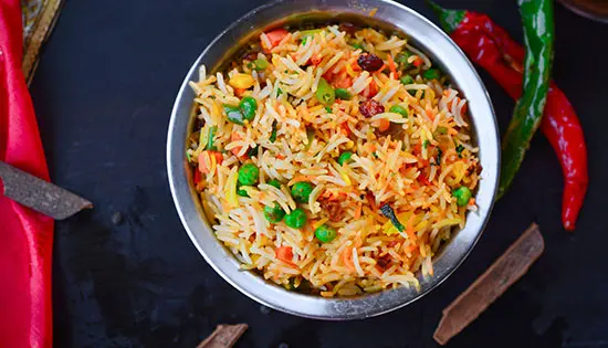 Bunte Reispfanne mit Gemüse wie Erbsen, Paprika und Karotten
